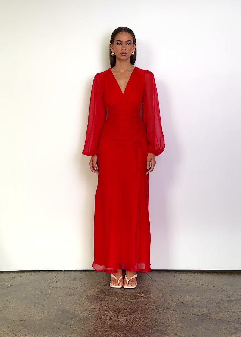 Video: Moonstruck Maxi Dress in Watermelon with a deep V-neckline, softly gathered bodice, sheer long blouson sleeves with elasticated cuffs, ruched waist with adjustable side tie detailing and a flowing maxi-length silhouette with a thigh-high side split.