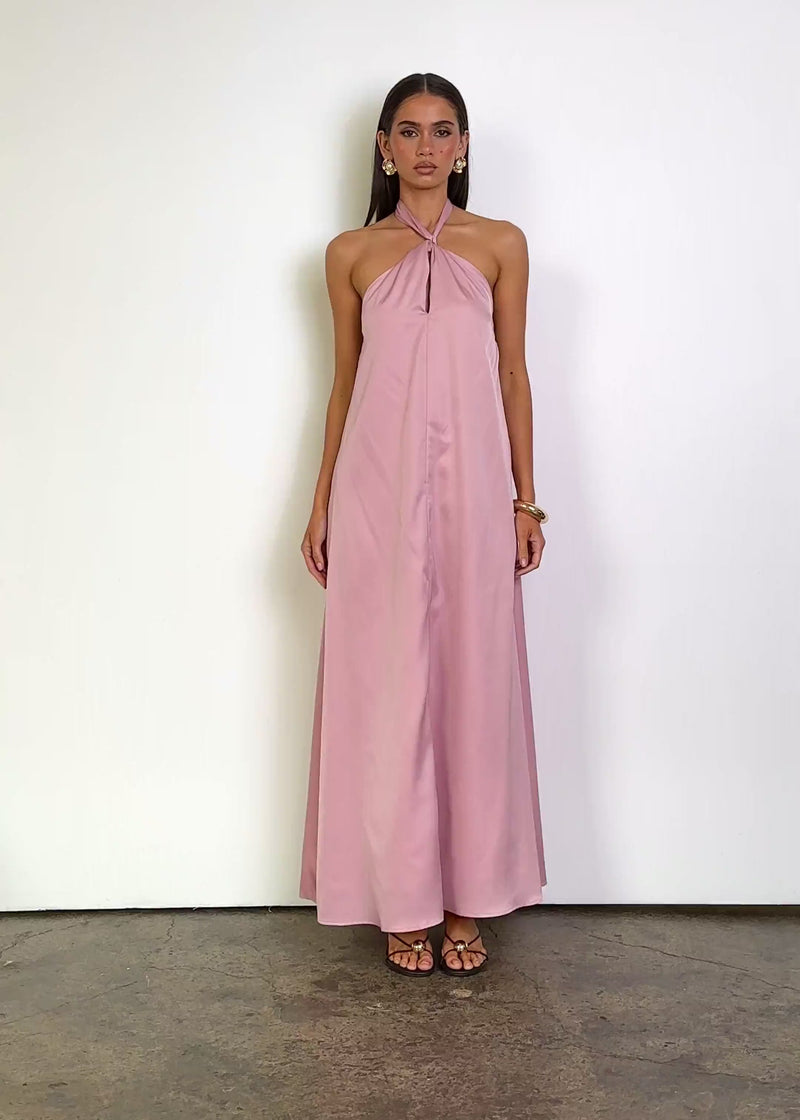 Video: Tenille Halter Maxi Dress in Blush with a twisted halter neckline, keyhole front detail, sleeveless open-shoulder design, relaxed flowing silhouette, side pockets and a floor-length hem with a soft fluid finish.